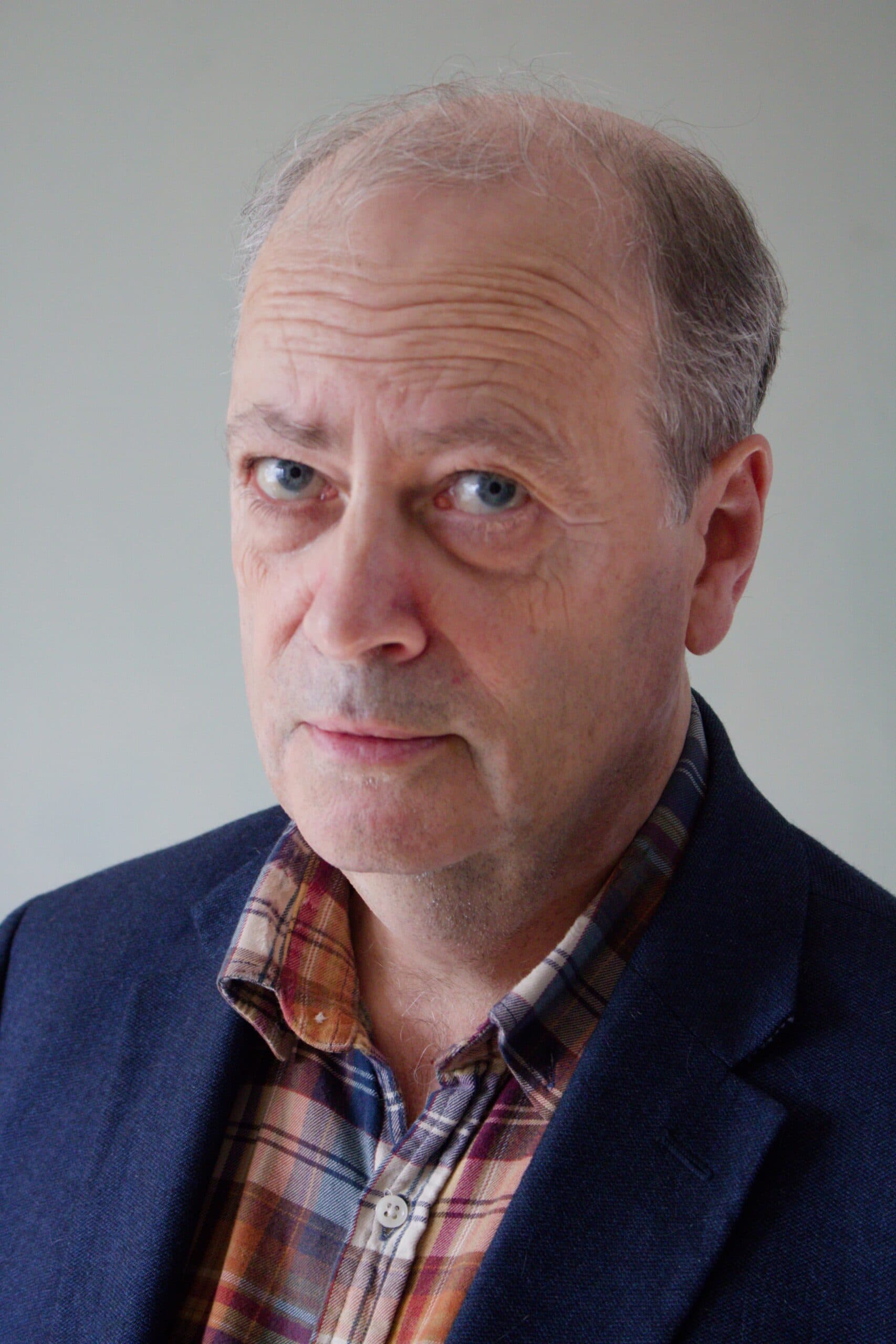 Portrait of Julian Masters in a navy jacket and checked shirt.